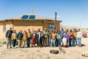 The 2024 Skip the Grid work crew from Heart of America gather in front of a Navajo Nation home newly fitted with solar panels.