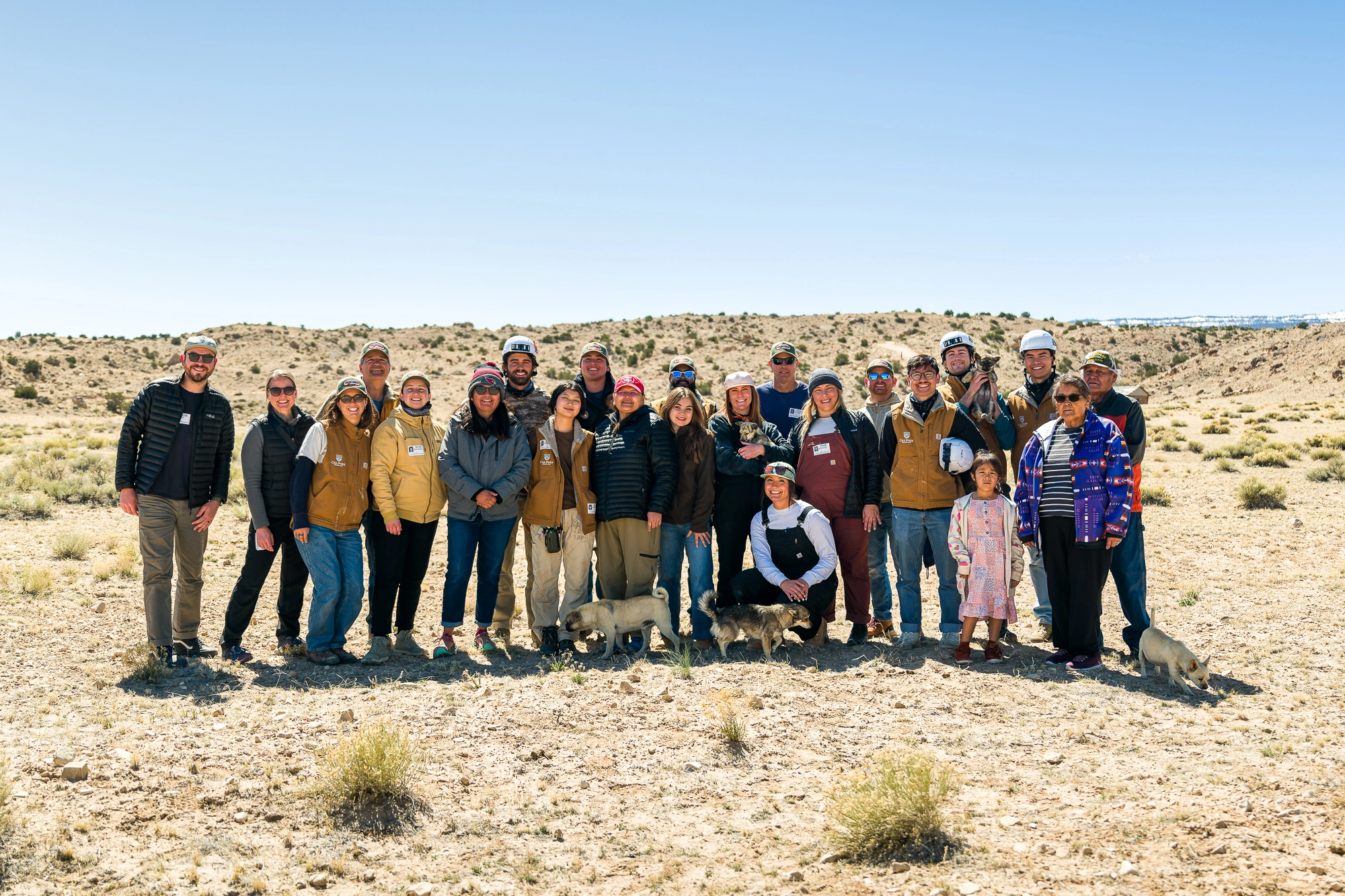 A group of people are posing for a photo in the desert against a blue sky.